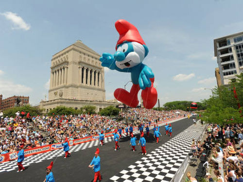 Giant Papa Smurf parade balloon flying over a crowd at the 500 Festival Parade